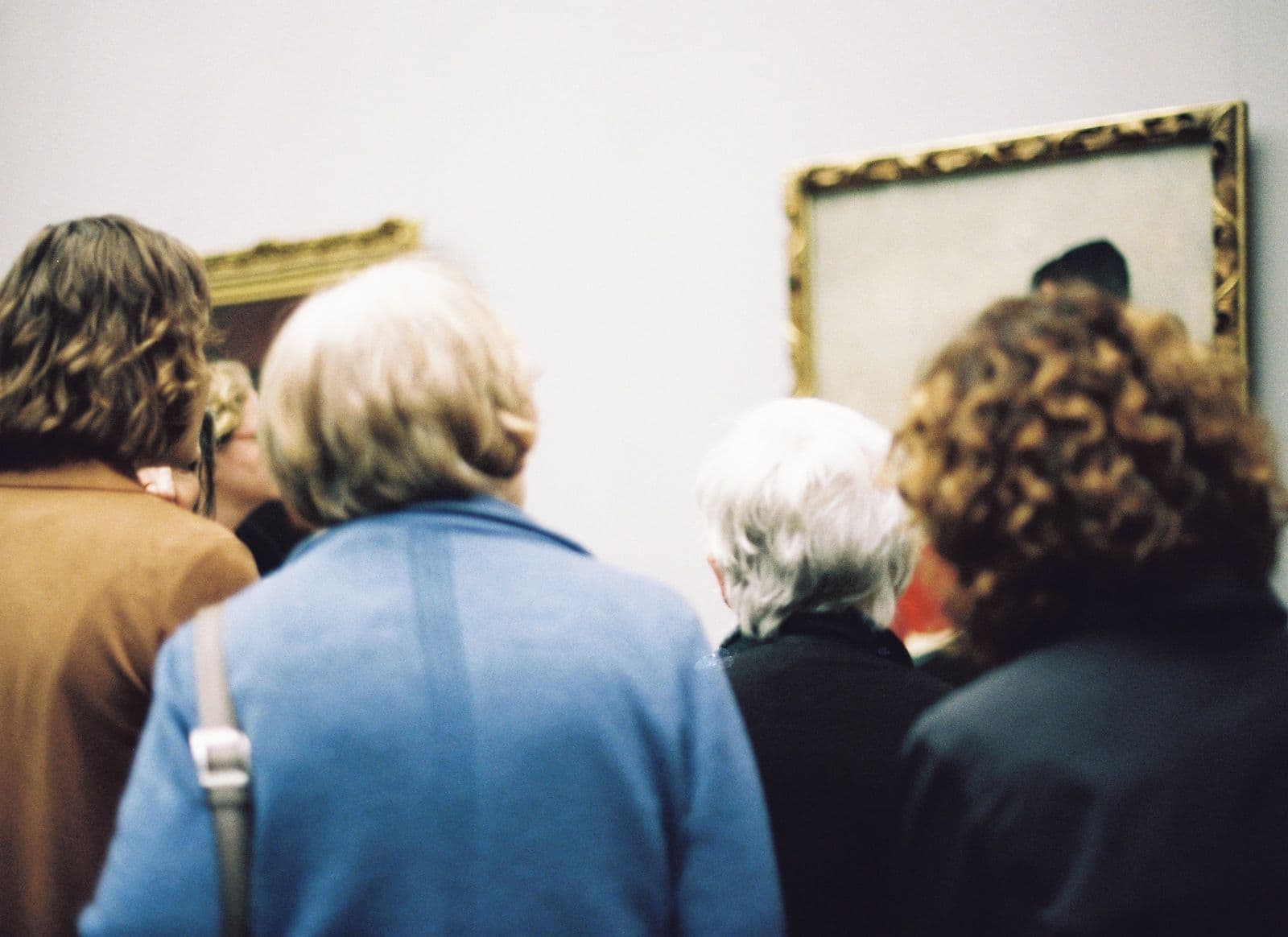 Visitantes a observar pinturas numa sala de museu