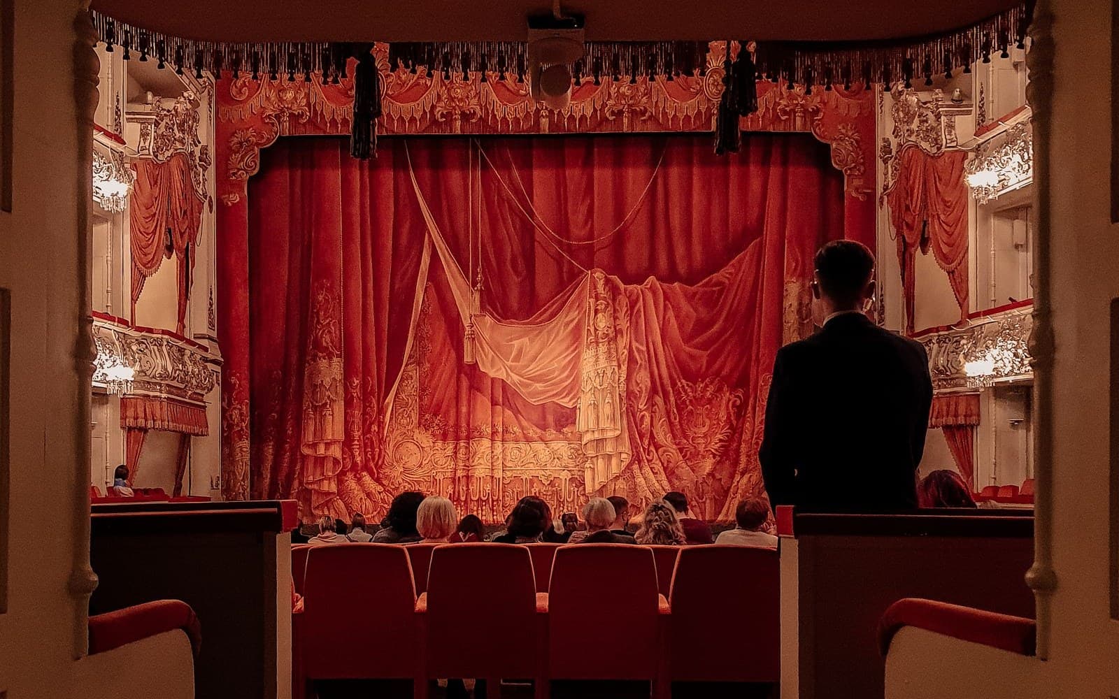 Assistente de frente de casa numa sala de teatro antes do espetáculo